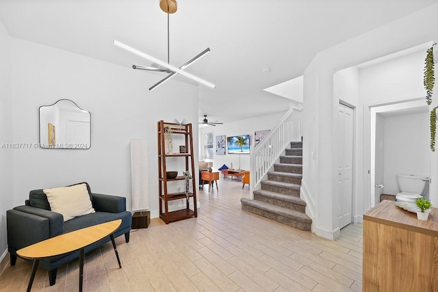 sitting room featuring ceiling fan with notable chandelier and light wood-type flooring