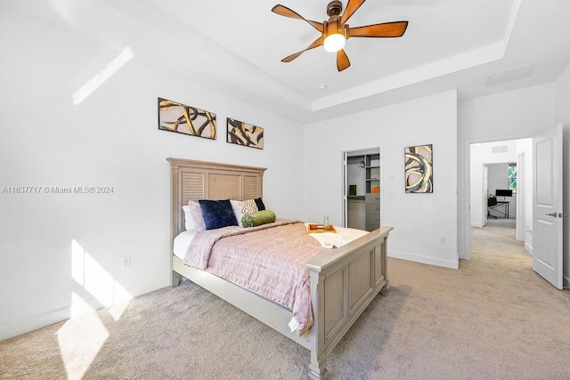 bedroom featuring light carpet, a raised ceiling, and ceiling fan