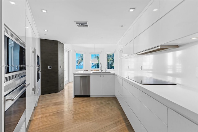 kitchen featuring white cabinets, sink, extractor fan, stainless steel appliances, and light wood-type flooring