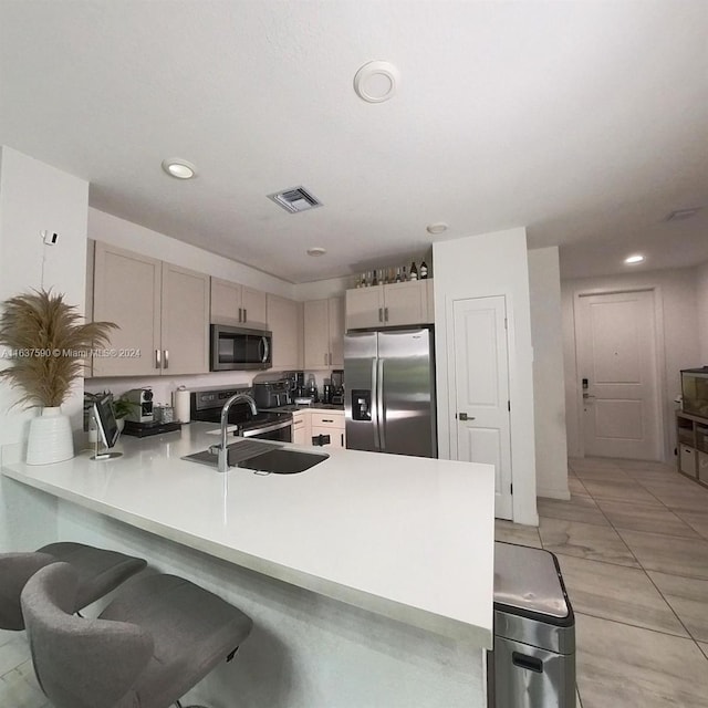 kitchen with appliances with stainless steel finishes, light tile patterned flooring, kitchen peninsula, and sink