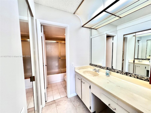 full bathroom featuring combined bath / shower with glass door, toilet, tile patterned flooring, vanity, and a textured ceiling