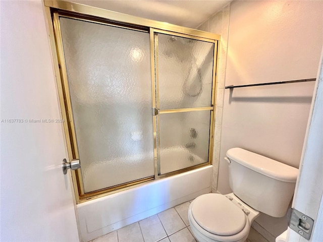 bathroom with combined bath / shower with glass door, tile patterned floors, and toilet