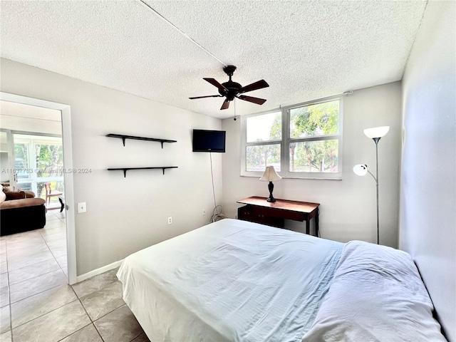 tiled bedroom with a textured ceiling, ceiling fan, and multiple windows