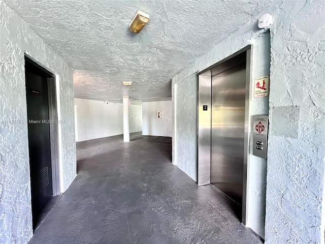 hallway with a textured ceiling and elevator