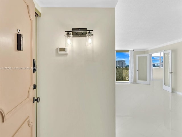 corridor with a textured ceiling, tile patterned flooring, and crown molding