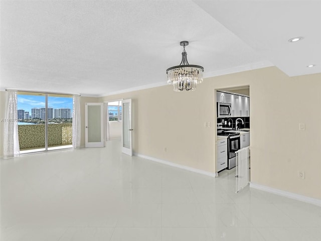 unfurnished living room with sink, a textured ceiling, ornamental molding, light tile patterned flooring, and a notable chandelier