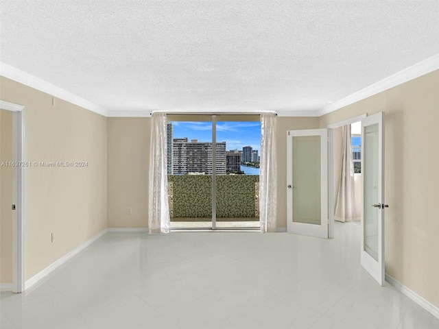 unfurnished room with a textured ceiling, french doors, light tile patterned floors, and ornamental molding