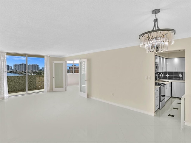 unfurnished living room with sink, light tile patterned floors, a textured ceiling, a chandelier, and ornamental molding