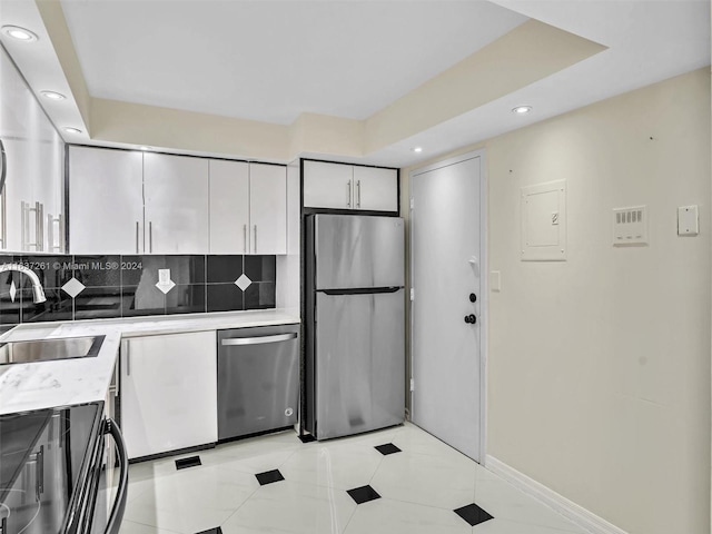 kitchen featuring tasteful backsplash, light tile patterned floors, electric panel, appliances with stainless steel finishes, and sink