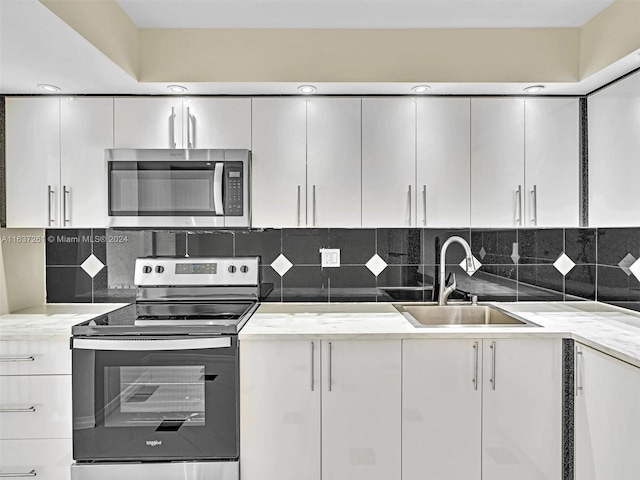 kitchen featuring stainless steel appliances, light stone counters, tasteful backsplash, and sink