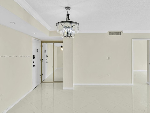 spare room with an inviting chandelier, ornamental molding, and light tile patterned floors