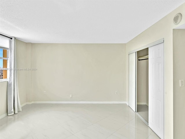 unfurnished bedroom with a closet, a textured ceiling, and light tile patterned floors