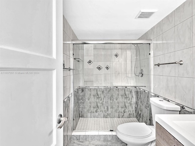 bathroom featuring vanity, tile patterned floors, walk in shower, tile walls, and toilet