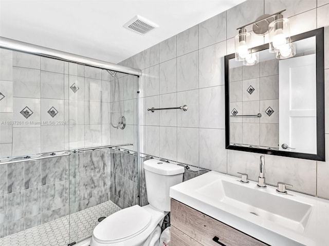 bathroom with vanity, tile walls, decorative backsplash, toilet, and a shower with door