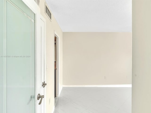 hall featuring light tile patterned floors and a textured ceiling