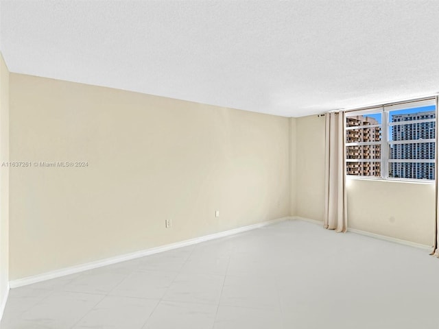 spare room featuring light tile patterned floors and a textured ceiling