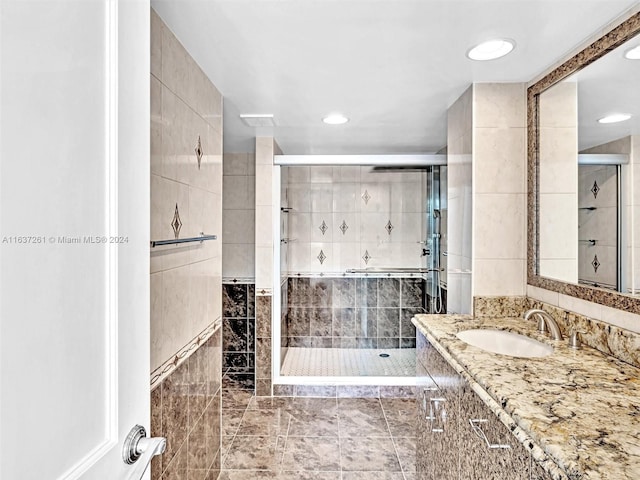 bathroom with tile patterned flooring, tile walls, vanity, and a tile shower