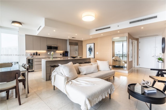 living room with sink, light tile patterned floors, and wine cooler