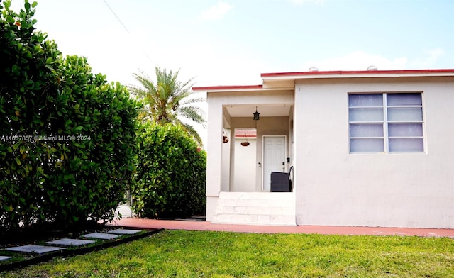 doorway to property with a lawn and stucco siding