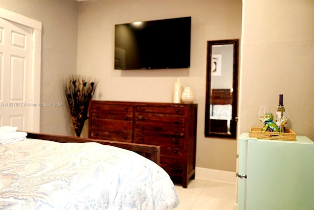 bedroom with light tile patterned floors, white fridge, and baseboards