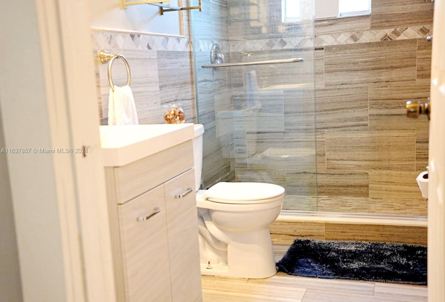 bathroom with tile walls, a stall shower, toilet, and vanity