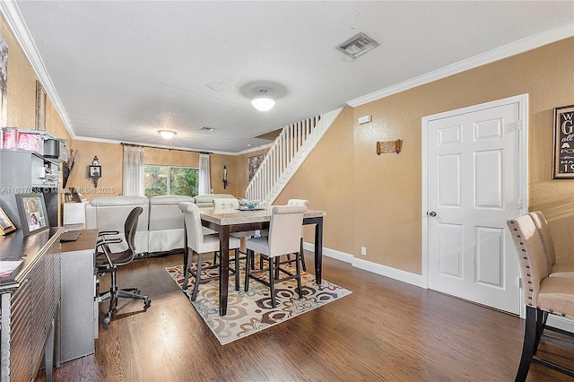 dining room featuring crown molding, wood finished floors, stairs, a textured wall, and baseboards