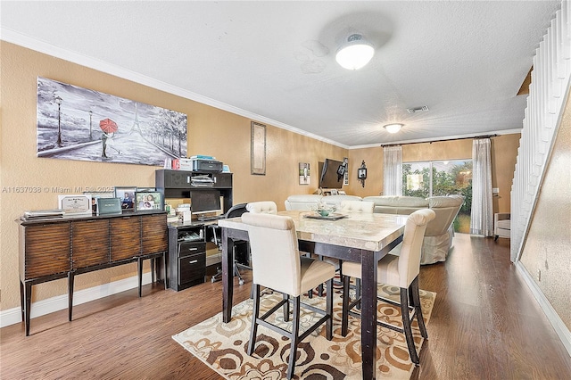 dining space featuring wood finished floors, crown molding, and baseboards