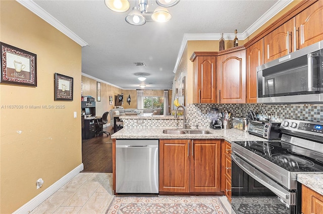 kitchen with stainless steel appliances, a sink, ornamental molding, open floor plan, and brown cabinets