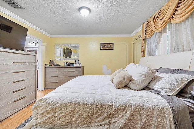 bedroom with ornamental molding, light wood-type flooring, and a textured ceiling
