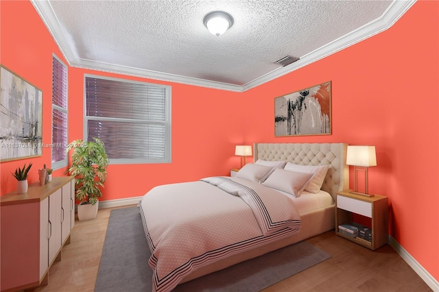 bedroom with a textured ceiling, light wood-style floors, crown molding, and baseboards