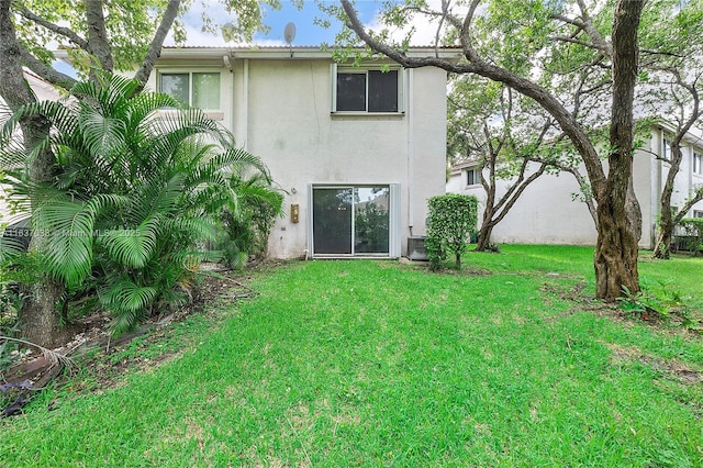 rear view of house featuring stucco siding and a lawn