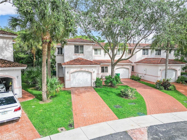 mediterranean / spanish-style house with stucco siding, decorative driveway, a tiled roof, and a front lawn