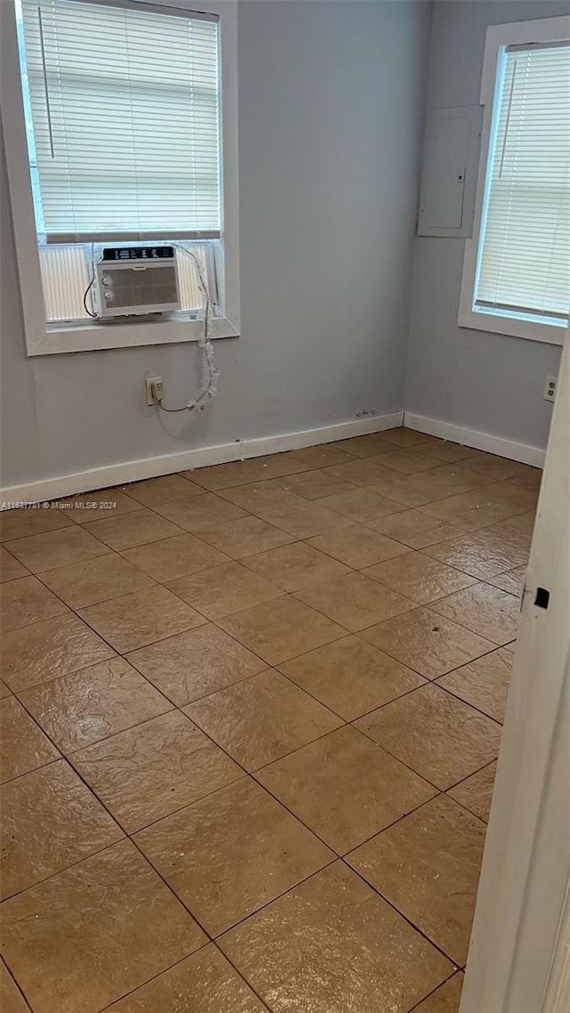 unfurnished room featuring light tile patterned floors, a wealth of natural light, and cooling unit