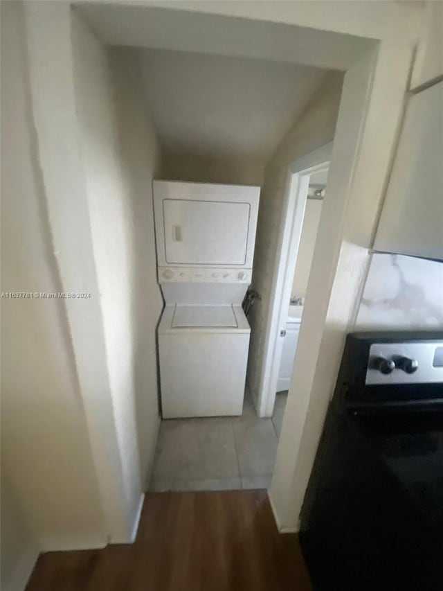 clothes washing area with light tile patterned floors and stacked washer and dryer