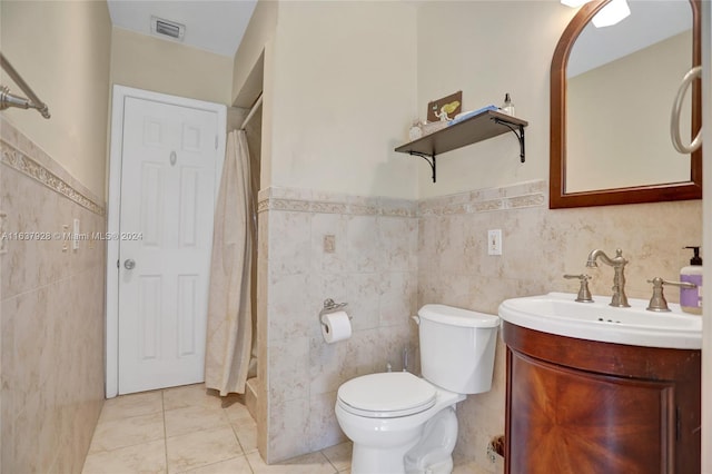 bathroom featuring tile patterned flooring, vanity, tile walls, and toilet