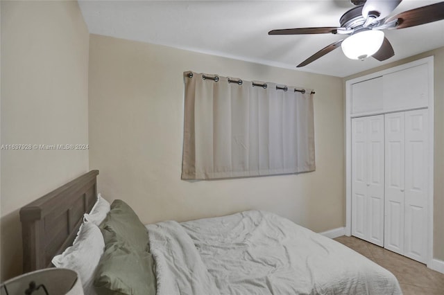 tiled bedroom with ceiling fan and a closet