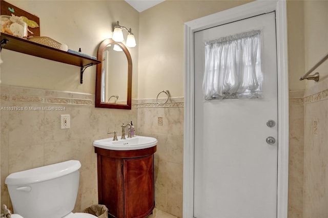 bathroom with vanity, tile walls, and toilet