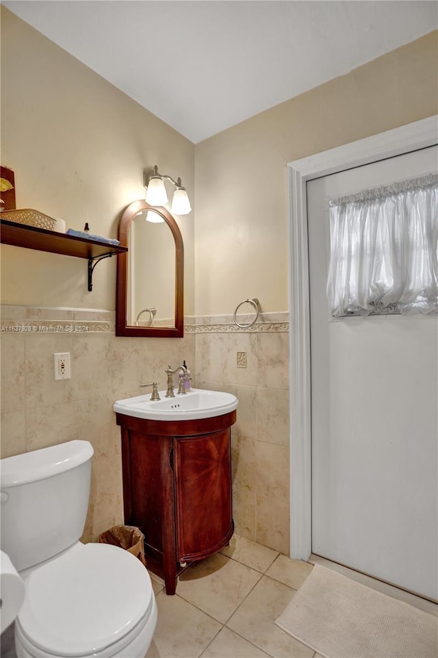 bathroom featuring toilet, vanity, tile patterned floors, and tile walls