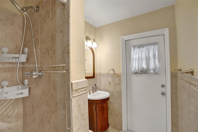 bathroom with tiled shower, vanity, tile patterned floors, and tile walls