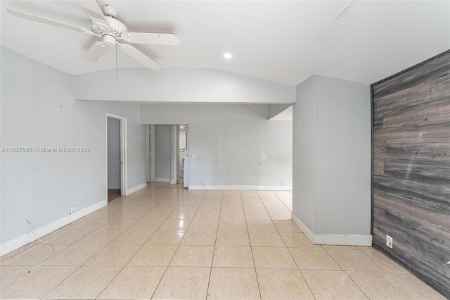 empty room featuring ceiling fan, light tile patterned floors, and vaulted ceiling