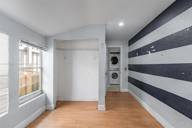 clothes washing area with stacked washing maching and dryer and light wood-type flooring