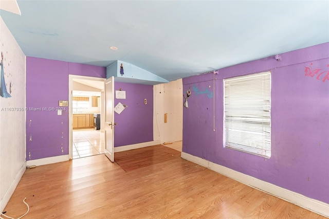 unfurnished room featuring light wood-type flooring and lofted ceiling