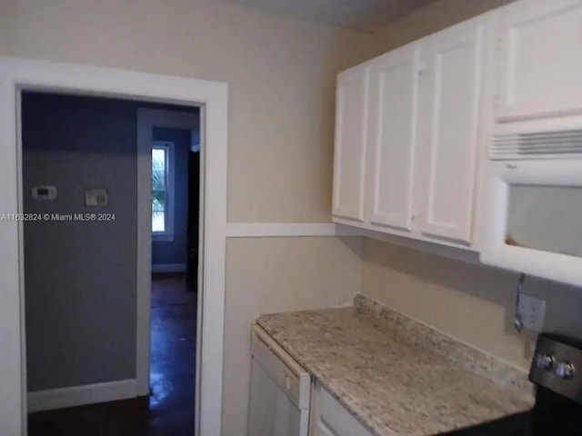 kitchen featuring light stone counters, white appliances, and white cabinets