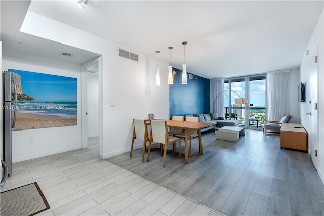 dining area with light hardwood / wood-style flooring and a wall of windows