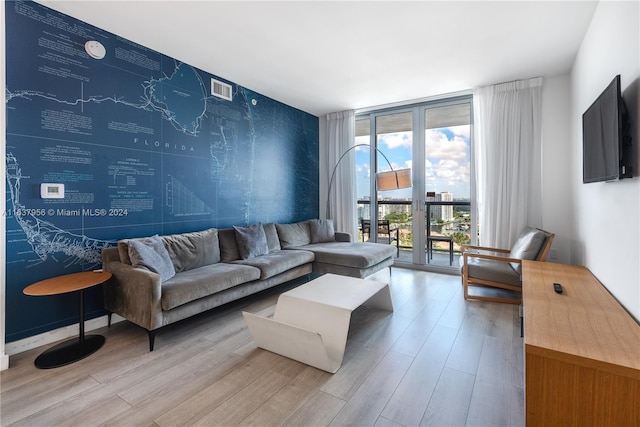 living area featuring visible vents, wood finished floors, baseboards, and expansive windows