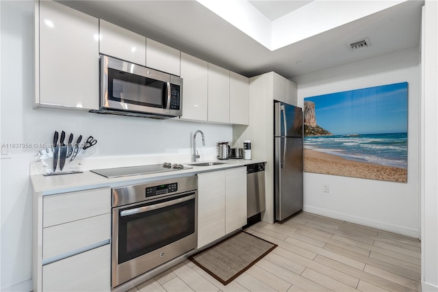 kitchen with white cabinets, light wood-type flooring, sink, and stainless steel appliances