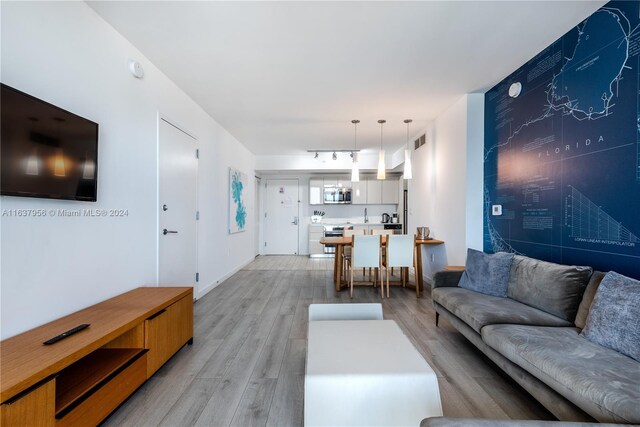 living area with light wood finished floors, visible vents, and rail lighting