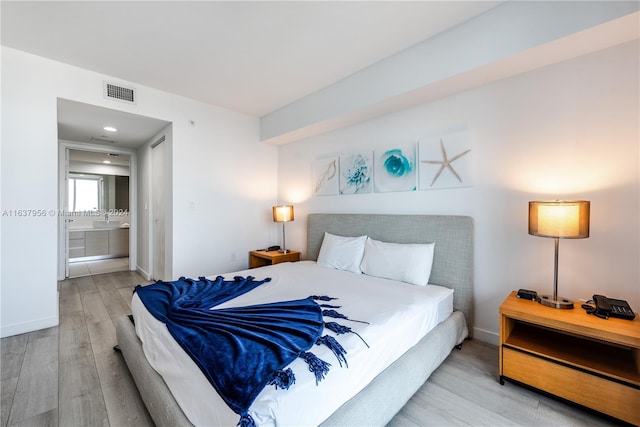 bedroom with light hardwood / wood-style flooring and ensuite bathroom