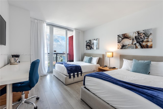 bedroom with access to exterior, a wall of windows, and wood finished floors