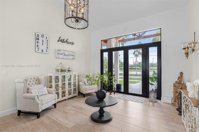 entryway with an inviting chandelier, a high ceiling, and light wood-type flooring